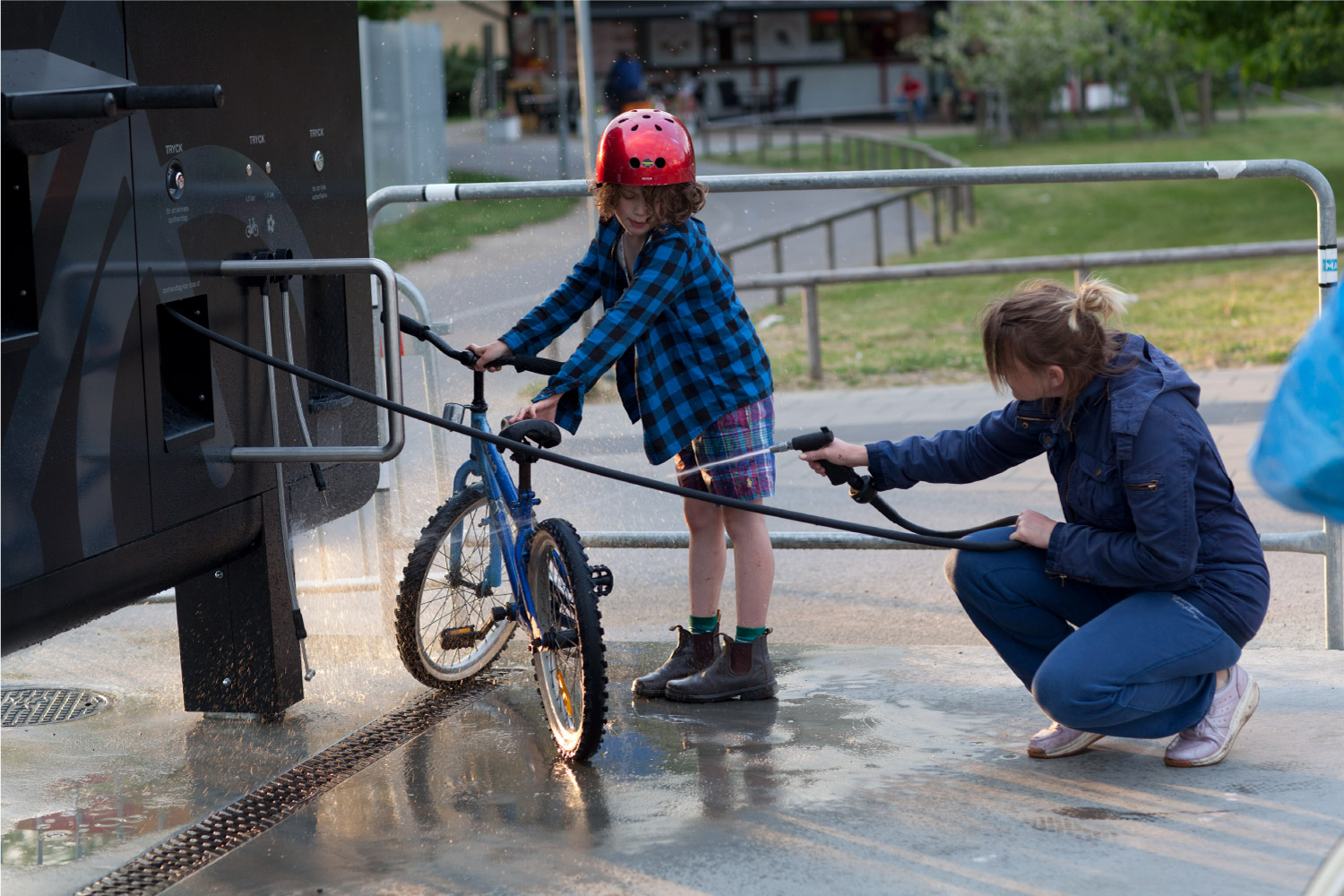 En kvinne og et barn renser sin sykkel på Sykkelservicestasjonen GRAND 3600